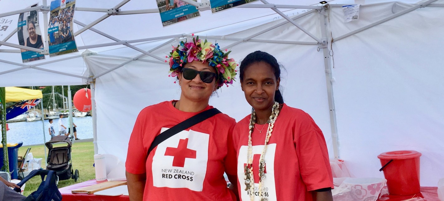 Two women pose for a photo at a Red Cross stand