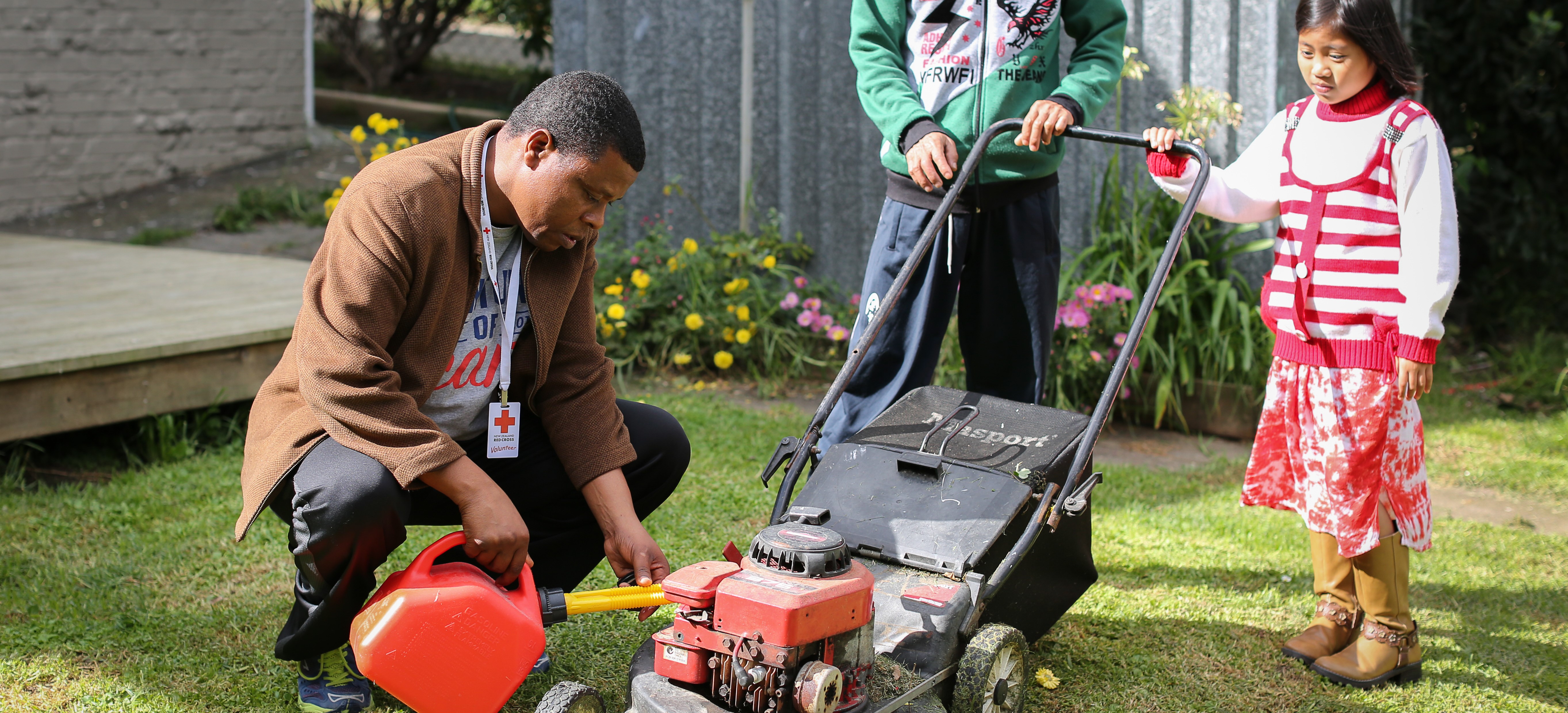 A man, a child, and an adult with a lawnmower.