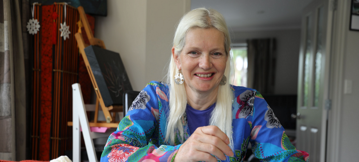 A woman smiling and knitting. 