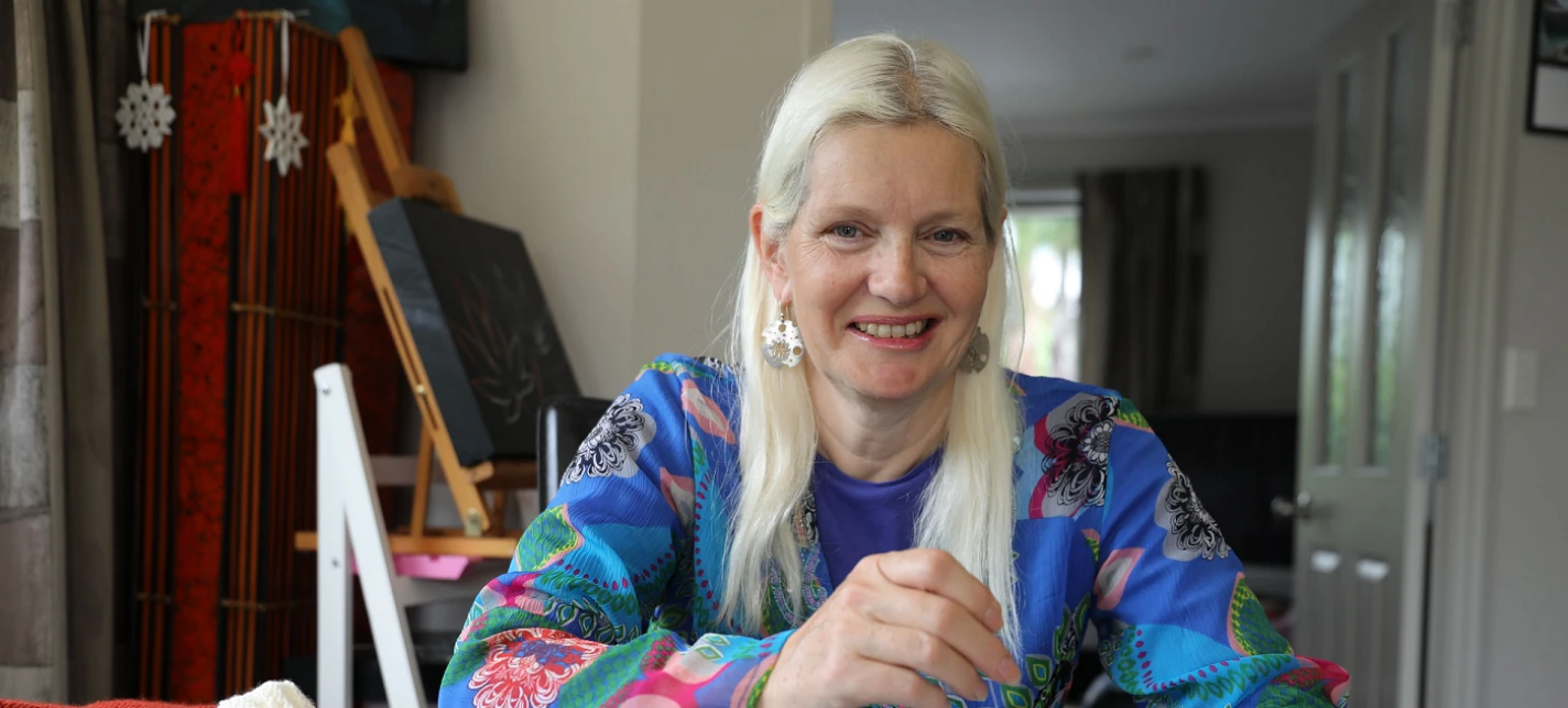 A woman smiling and knitting.
