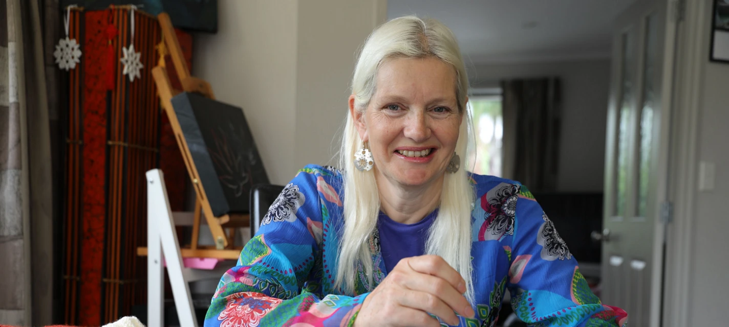 A woman smiling and knitting. 