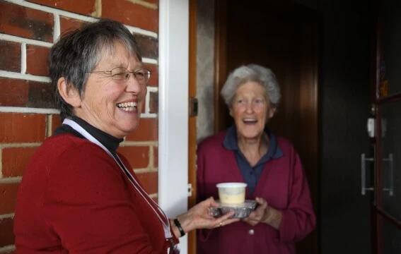 A woman giving another woman a packaged meal.