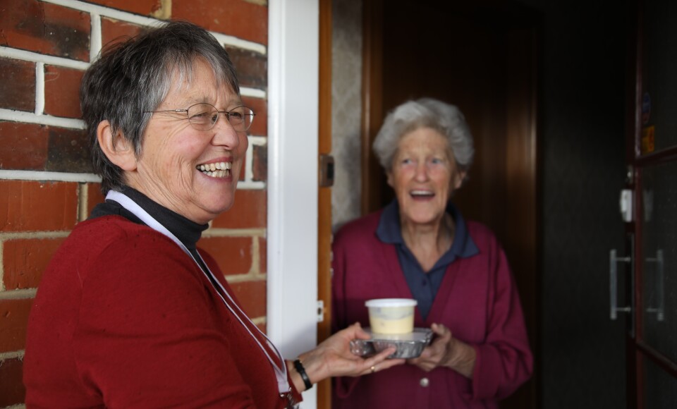 A woman giving another woman a packaged meal. 