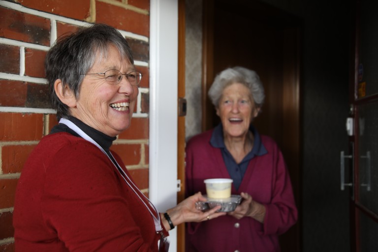 A woman giving another woman a packaged meal.