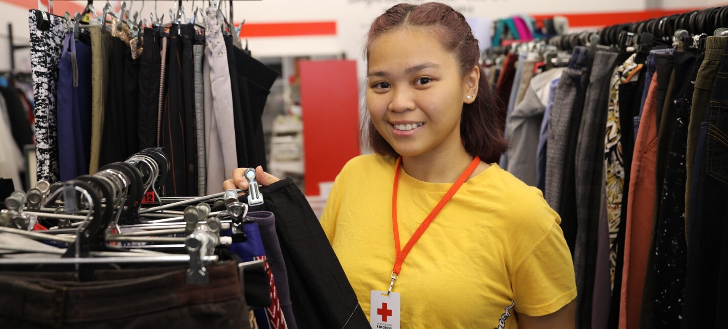 A team member looks through a rail of clothing in a Red Cross shop