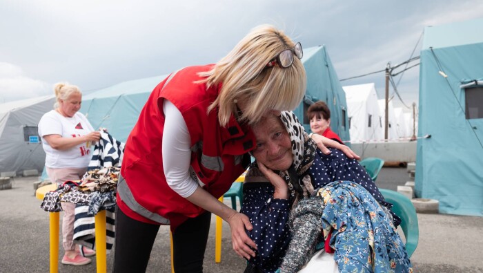 Red Cross worker supports woman in emergency shelter
