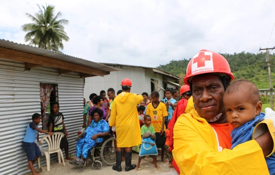 A member of the International Federation of Red Cross and Red Crescent Societies holds a child during an IFRC emergency drill in Fiji.
