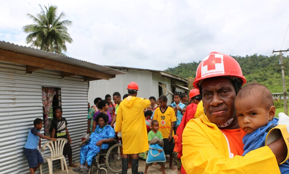 A member of the International Federation of Red Cross and Red Crescent Societies holds a child during an IFRC emergency drill in Fiji.