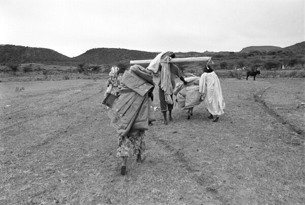 Adults and children carrying canvas tent materials.