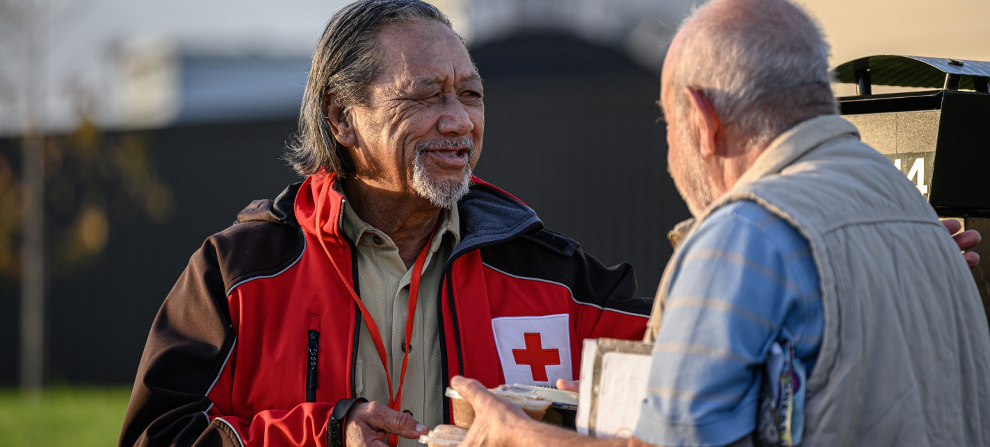 A man giving another man a packaged meal.